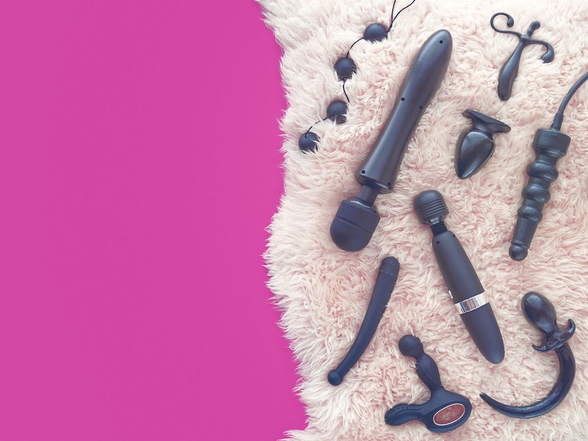 Sex toys (dildo, vibrator, anal plug, love balls and other) are on light sheep's fur. There is a fuchsia-colored background with an blank space. The image is suitable for sex shop advertising